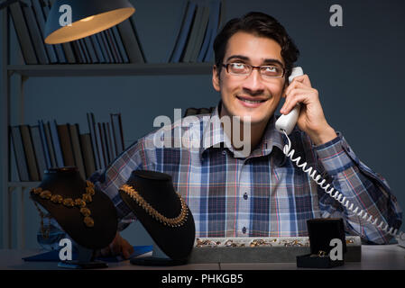 Giovane maschio gioielliere lavorando di notte nel suo laboratorio Foto Stock