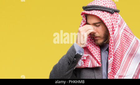 Giovane bello arabian uomo con capelli lunghi che indossa keffiyeh su sfondo isolato stanco strofinando il naso e gli occhi sensazione di stanchezza e mal di testa. Lo stress di un Foto Stock
