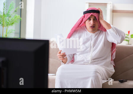 Imprenditore arabo guardando la tv a casa Foto Stock