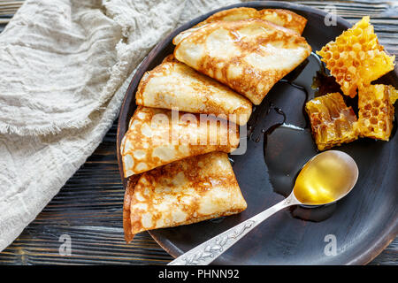 Crepes con miele su una lastra di legno. Foto Stock