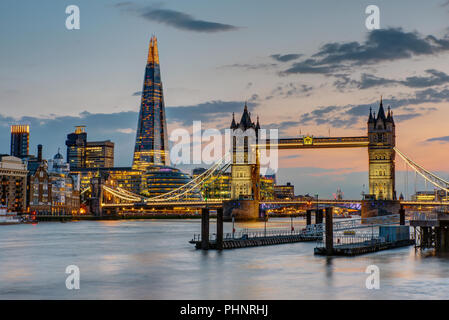 Il Tower Bridge di Londra dopo il tramonto con il Coccio nel retro Foto Stock