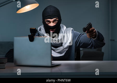 Attentati ladro con la pistola lavorando al computer Foto Stock