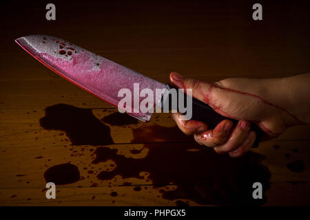 La mano di un omicida o killer intriso di sangue e il possesso di un coltello pronto ad uccidere. Foto Stock