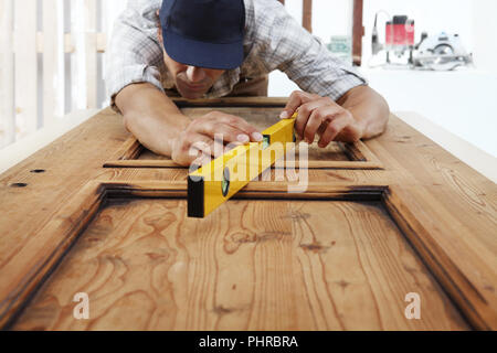 Carpenterr lavorano il legno la misurazione con livella a bolla Foto Stock