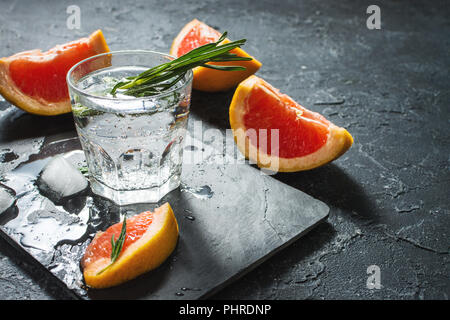 Cocktail con succo di pompelmo, ghiaccio e rosmarino su pietra scura sullo sfondo. Foto Stock