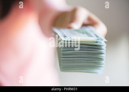 Soft focus sulla donna mani proponendo denaro US Dollar Bills a voi. Foto Stock