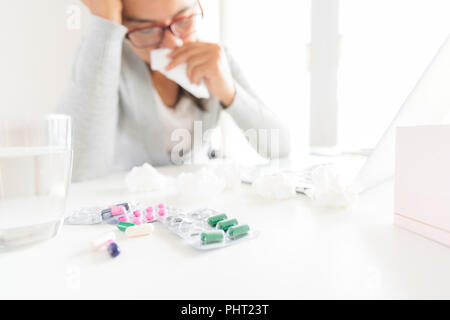 Young business woman malati in ufficio, mano azienda s tessuto e neezing in un tessuto bianco. portatile sul tavolo. Sanità e medicina concetto. Foto Stock