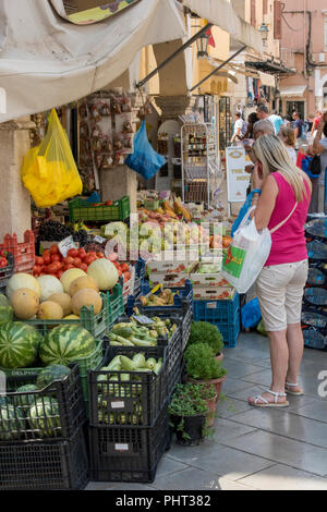 Donna shopping per verdure a un fruttivendolo frutta e verdura in stallo su un mercato greco nella città vecchia di kerkira, Corfù, Grecia. Foto Stock