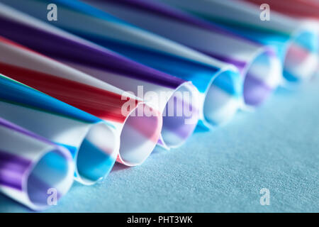 Bevanda a strisce colorate macro cannucce isolato su sfondo blu Foto Stock