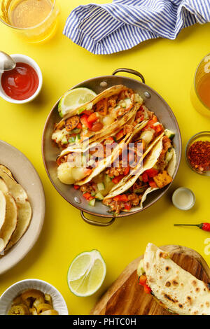 Immagine aerea messicana di tacos con chili con carnes e formaggio grattugiato servito su uno sfondo giallo Foto Stock