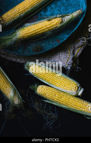 Dolce giallo sulla pannocchia di mais, su un tavolo scuro Foto Stock