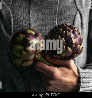 Un uomo con due carciofi Foto Stock