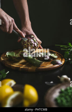 Un uomo di preparare un carciofo Foto Stock