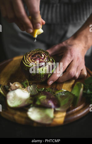 Gocce di limone spremuto a un carciofo Foto Stock