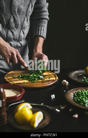 Un mans mani tritare il prezzemolo durante la preparazione di un pasto Foto Stock