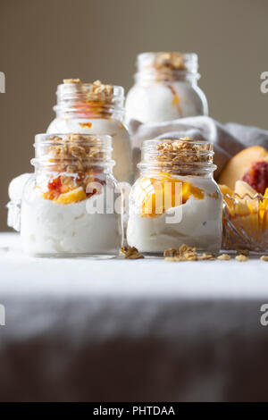 Colazione senza glutine per andare - yogurt greco, pesca, mango e granola con miele e polline di api. Foto Stock