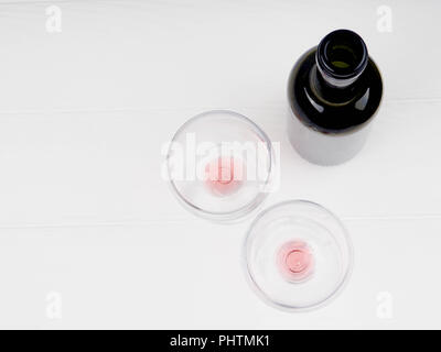 Bicchiere di vino e una bottiglia su un sfondo di legno, bottiglia di vino rosso e bicchieri giacente su un vecchio tavolo di legno. Vista ravvicinata, focus sulla bottiglia di rosso w Foto Stock