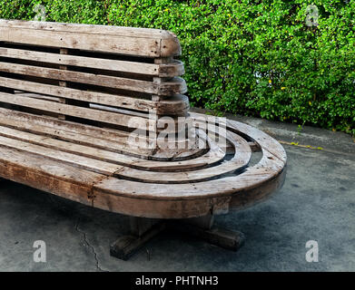 Bella decorativi in legno marrone una panchina nel parco in piedi su un marciapiede. Foto Stock