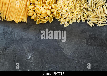 Pasta secca dello sfondo. Diversi di pasta su sfondo scuro. Lay piatto. Vista superiore Foto Stock