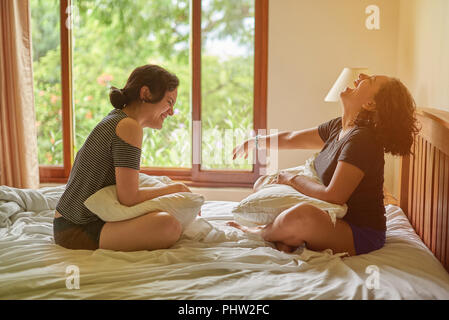Felice di parlare due womans seduto in camera sul letto Foto Stock