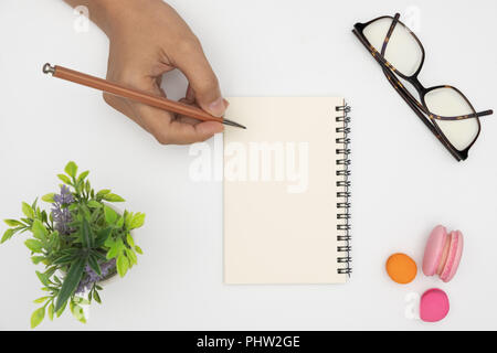 Vista dall'alto per notebook aperto, matita, impianti incapsulate, bicchieri e amaretto bianco su sfondo scrivania. Foto Stock