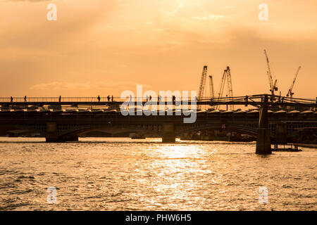 Millennium Bridge al tramonto come pedoni a piedi attraverso il Fiume Tamigi Foto Stock