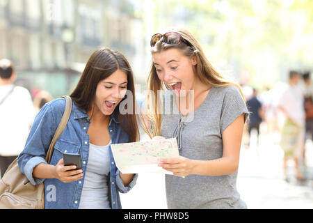 Due entusiasti turisti in viaggio per trovare la posizione in una guida della carta in strada Foto Stock