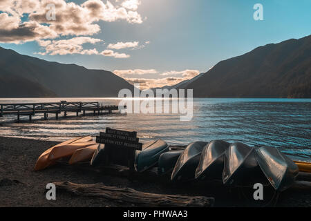 Il lago di Crescent nel tardo pomeriggio con una fila di kayak e canoe sdraiato sulla spiaggia, il Parco Nazionale di Olympic, nello stato di Washington, USA. Foto Stock