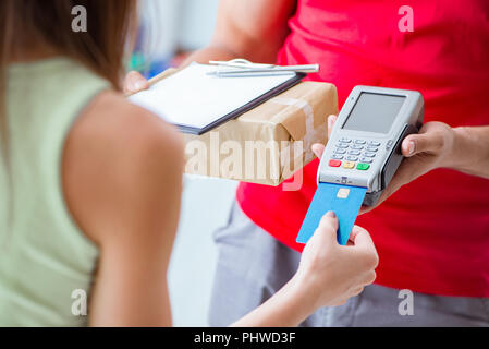 La consegna di pacchi essendo pagato con pos e carta di credito Foto Stock