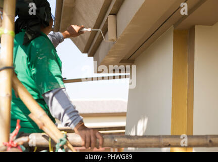 Pittore su impalcatura di legno verniciatura esterna House Foto Stock