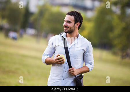 Giovane imprenditore è mangiare apple presso il parco. Foto Stock