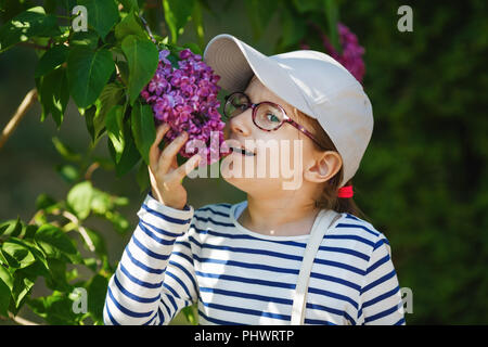 Bambino ragazza profumati lillà fiori nel giardino. Messa a fuoco selettiva. Foto Stock