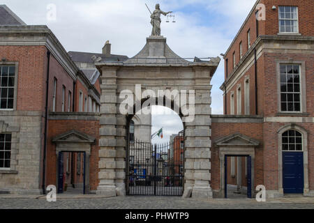 Un gate nel Castello di Dublino, Irlanda con la statua della Madonna della giustizia in cima che tiene una spada in una mano e la bilancia della giustizia nell'altro. Foto Stock