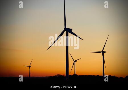 Le turbine eoliche in silhouette su terreni agricoli al tramonto, Cresent le Marsh, Lincolnshire, Regno Unito Foto Stock