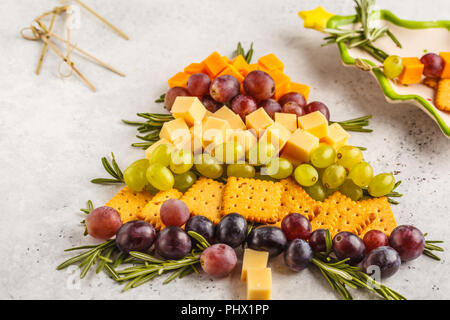 Albero di Natale da antipasti: formaggio, uva, cracker. Gastronomia natalizia concetto, sfondo bianco. Foto Stock