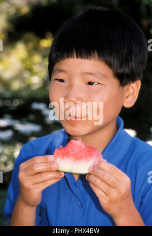 Giovane ragazzo coreano mangiando anguria fuori © Myrleen Pearson ..Ferguson Cate Foto Stock