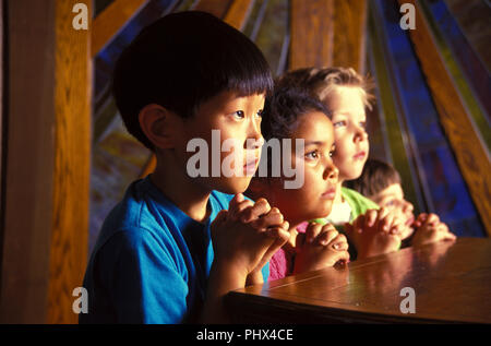 Etnico gruppo misto di giovani bambini cristiani pregare in chiesa il signor © Myrleen Pearson ...Ferguson Cate Foto Stock