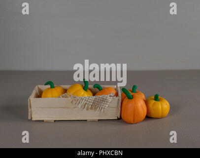 Artigianale di gabbia in legno riempita con orange zucche e alcune sul lato con uno sfondo marrone. Foto Stock