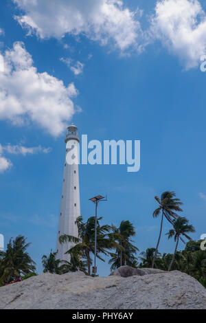 Faro contro il cielo azzurro nuvoloso in una piccola isola di Baltung, Indonesia Foto Stock