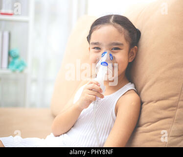 Carino bambino asiatico paziente terapia di inalazione dalla maschera di inalatore con flusso di morbida del fumo da broncodilatatore. Foto Stock