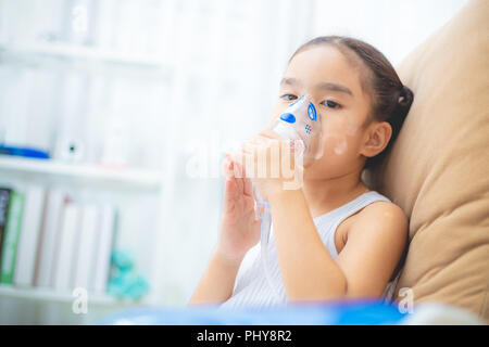 Carino bambino asiatico paziente terapia di inalazione dalla maschera di inalatore con flusso di morbida del fumo da broncodilatatore. Foto Stock