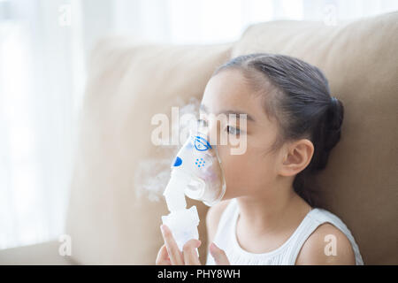 Carino bambino asiatico paziente terapia di inalazione dalla maschera di inalatore con flusso di morbida del fumo da broncodilatatore. Foto Stock