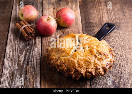 La torta di mele in padella in ghisa su tavola in legno rustico, tradizionale autunno accogliente dessert Foto Stock