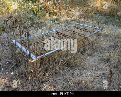 Stravagante metallo vecchio letto francese telaio nascosto in erba lunga presso un privato casa francese e il giardino in estate Foto Stock