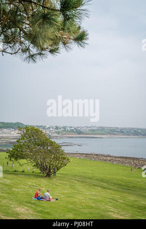 Marazion, Inghilterra - Maggio 2018 : Turisti seduti su un'erba avente picnic sulla collina di Monte San Michele isola fortezza giardini, Cornwall, Regno Unito Foto Stock