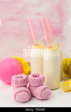 Baby doccia tavolo decorativo con spazio copia, rosa bambina stivaletti e bottiglie di latte in background color pastello, idea di bambino, doccia decor Foto Stock