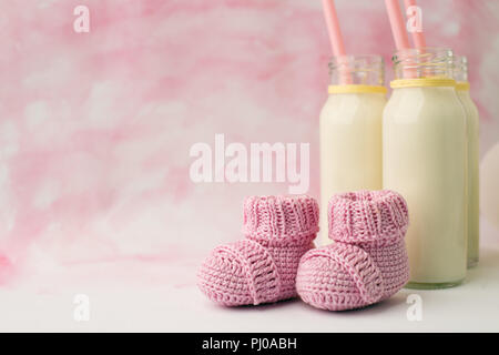 Baby doccia tavolo decorativo con spazio copia, rosa bambina stivaletti e bottiglie di latte in background color pastello, idea di bambino, doccia decor Foto Stock