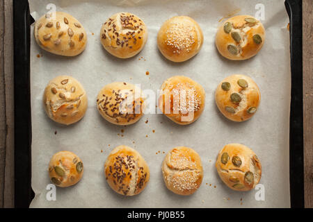 Freschi Fatti in casa panini hamburger con sesamo, zucca, lino, semi di girasole sul vassoio, concetto di burger e cibo fatto in casa. Mini challah Foto Stock