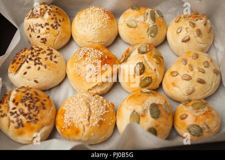 Freschi Fatti in casa panini hamburger con sesamo, zucca, lino, semi di girasole sul vassoio, concetto di burger e cibo fatto in casa. Mini challah Foto Stock