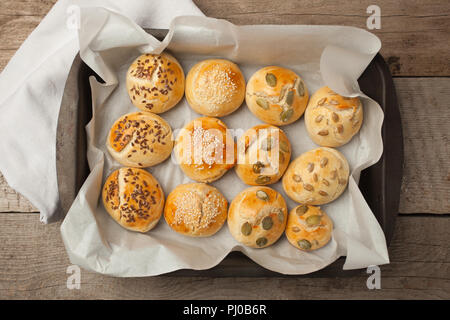 Freschi Fatti in casa panini hamburger con sesamo, zucca, lino, semi di girasole sul vassoio, concetto di burger e cibo fatto in casa. Mini challah Foto Stock